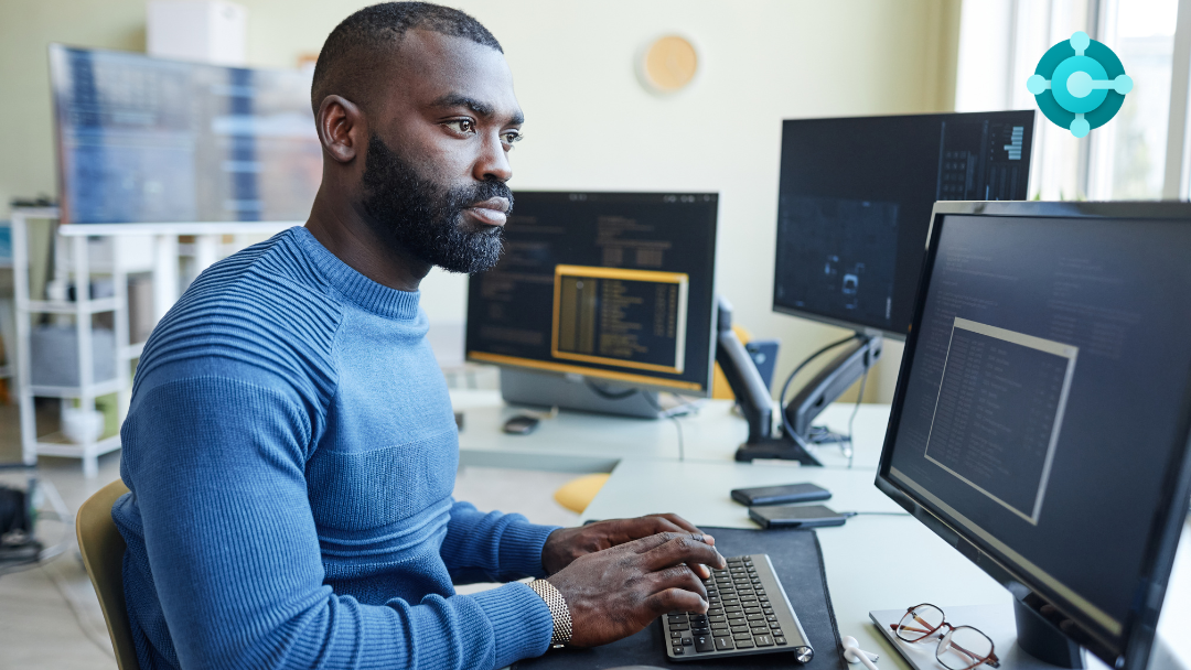man sits in front of computers working, the Business Central logo in the corner